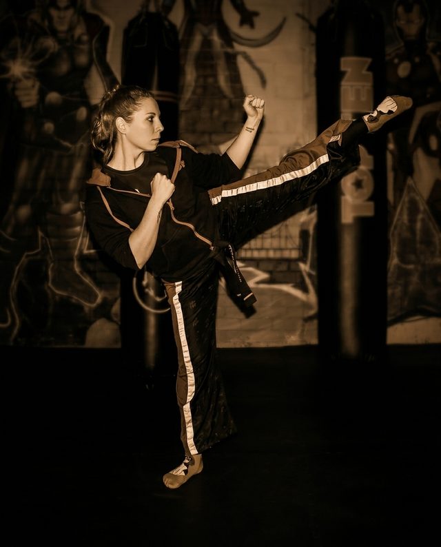 Celeste Currie throwing a head-height kick in a boxing gym